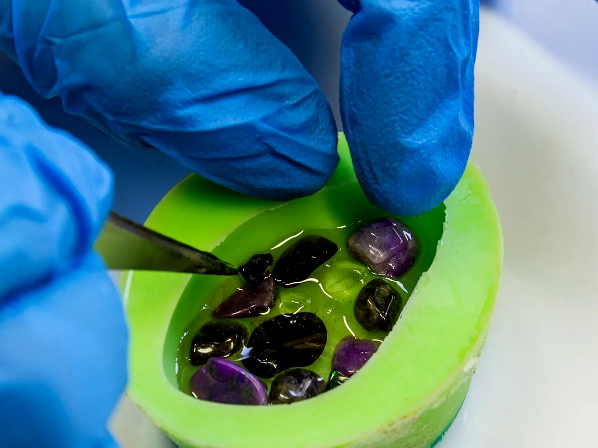 Edelsteine werden von Hand in die Gussform gelegt – OZ Orgonite Manufaktur